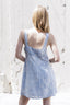 Woman wearing a light blue dress against a white textured wall