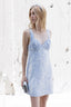 Woman wearing a light blue dress against a white textured wall
