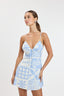 Woman wearing a light blue and white patterned dress on a plain background