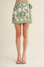Green and white patterned skirt worn by a person on a beige background