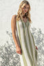 Woman wearing a green and white striped dress against a textured white wall.