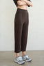 Person wearing brown high-waisted pants with a plain background