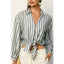 Woman wearing a blue and white striped shirt tied at the waist with a neutral background