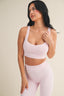 Woman wearing a light pink sports bra and leggings on a beige background