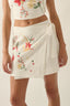 Person wearing a white floral skirt and top on a plain background