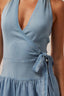 Blue dress with a deep neckline and tied waist on a neutral background