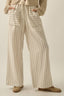 Person wearing beige and white striped pants with a neutral background