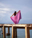 Woman with a pink scarf standing on a wooden pier by the water