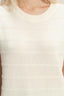 Close-up of a person wearing a white ribbed knit sleeveless top.