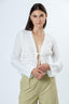 Woman wearing a white lace top with a plain background