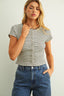 Woman wearing a striped shirt and blue jeans against a plain background