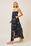 Woman wearing a navy floral strapless dress on a beige background