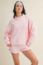 Woman wearing a pink sweatshirt and shorts set on a beige background