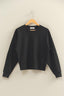 Black sweatshirt on a wooden hanger against a beige wall