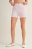 Person wearing light pink floral shorts on a plain background