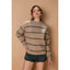 Woman wearing a striped sweater and shorts against a beige background