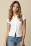 Woman wearing a white blouse and blue jeans against a beige background