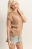 Woman wearing a beige sweater and denim shorts on a plain background