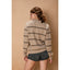 Woman wearing a beige sweater with black stripes and denim shorts against a beige background