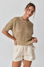 Woman wearing a beige knitted top and shorts on a plain background