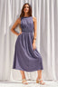 Woman wearing a purple dress standing against a white curtain