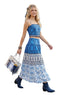 Woman in a blue and white patterned dress walking outdoors with a crowd in the background.