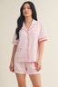Woman wearing a pink pajama set with a subtle pattern on a beige background