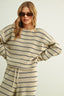 Woman wearing a striped dress with sunglasses on a plain background