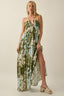 Woman wearing a floral dress with a slit on a plain background