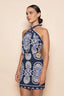 Woman wearing a navy blue dress with white and blue floral patterns on a beige background