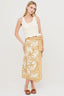 Woman wearing a white sleeveless top and yellow patterned skirt on a white background