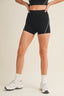Person wearing black athletic shorts on a beige background