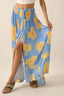 Woman wearing a blue floral dress with a slit on a beige background
