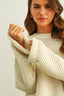 Woman wearing a beige knitted sweater against a plain background