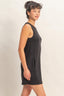 Woman wearing a black sleeveless dress against a plain background