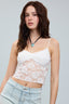 Woman wearing a white lace top and light blue jeans against a gray background