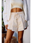 Person wearing a white outfit with shorts and a cardigan in an outdoor setting.