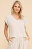 Woman wearing a beige ribbed top and pants against a beige background