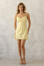 Woman wearing a yellow slip dress against a plain background