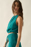 Woman wearing a teal top and skirt set against a plain background