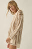 Woman wearing a beige knitted cardigan against a plain background