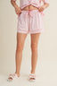 Person wearing pink floral pajama shorts on a beige background