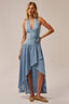 Woman wearing a light blue dress with a halter neck and high-low hem on a beige background