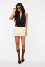 Woman wearing a black sleeveless top and white ruffled skirt on a white background