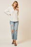Woman wearing a white button-up shirt and ripped jeans on a plain background