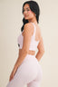 Woman wearing a white sports bra and leggings on a beige background