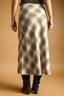 Person wearing a plaid skirt on a beige background