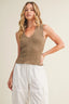 Woman wearing a brown knitted sleeveless top and white pants against a beige background