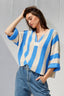 Woman wearing a blue and beige striped sweater against a gray background
