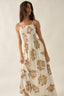 Woman wearing a white dress with brown floral patterns against a plain background